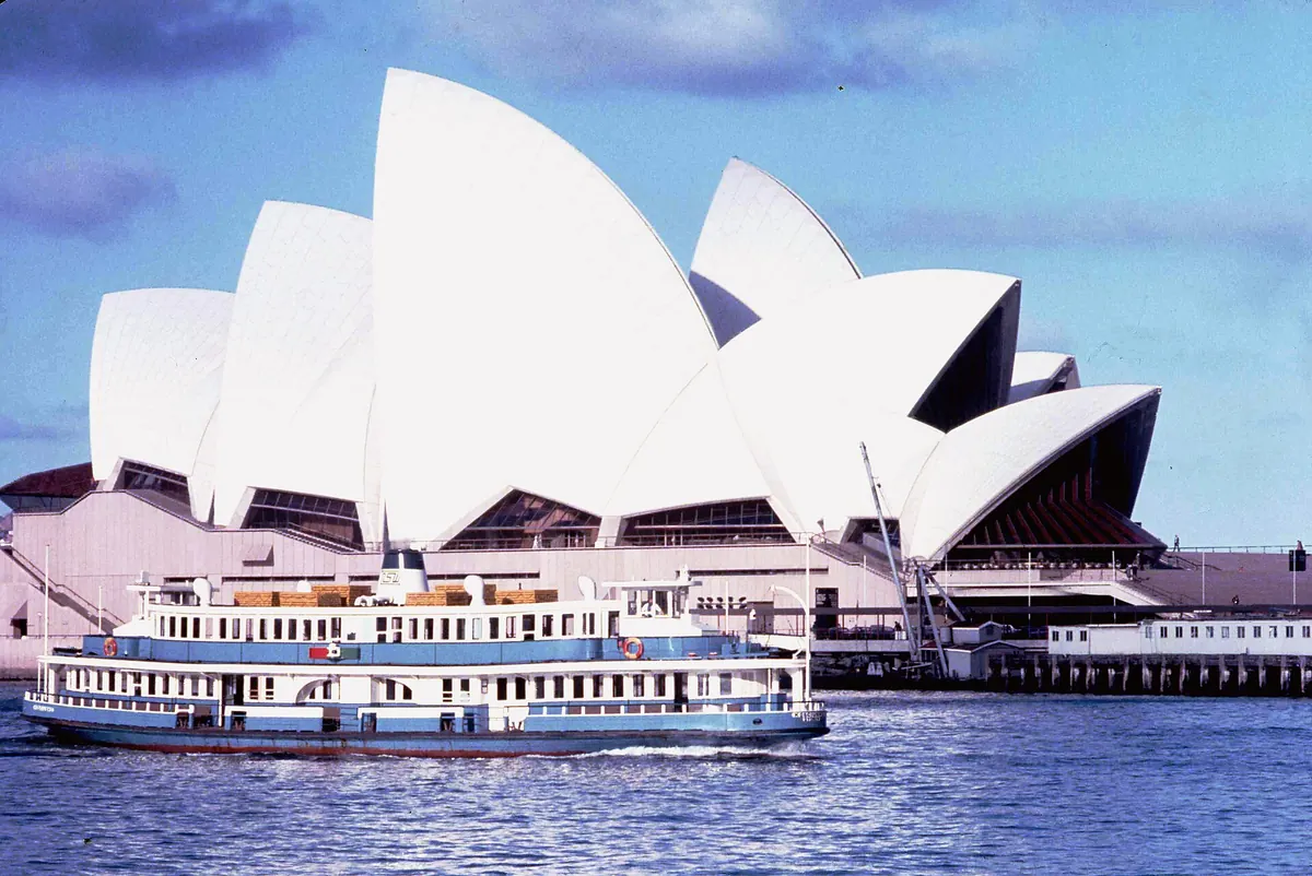 Un traghetto blu e bianco di Sydney che passa davanti alla Sydney Opera House appena inaugurata nell'ottobre 1973, con le conchiglie bianche sullo sfondo